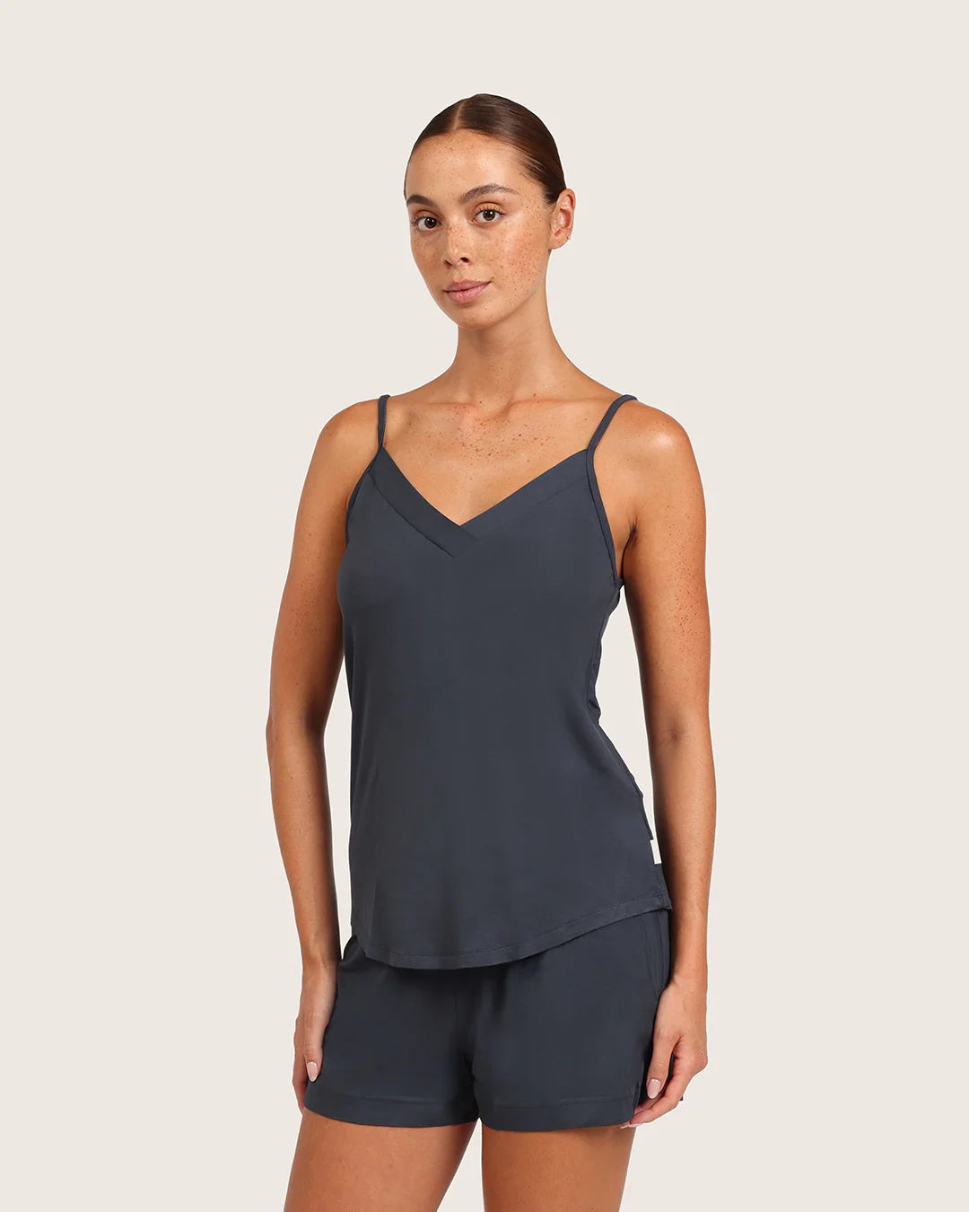 Woman wearing a dark blue tank top and shorts on a beige background
