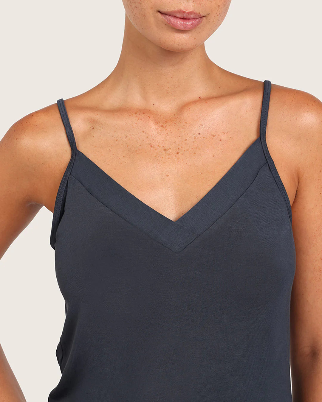 Navy blue spaghetti strap top worn by a person on a light gray background