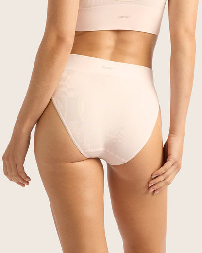 Person wearing a light pink high-waisted underwear on a plain background