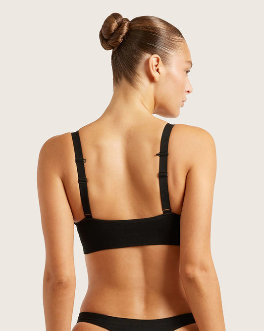 Woman wearing a black bra and underwear set on a light background