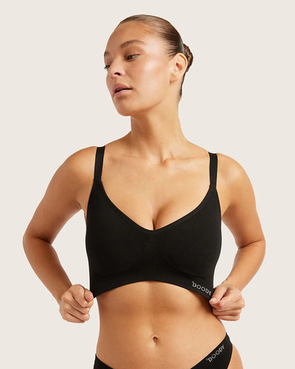 Woman wearing a black sports bra with visible branding on a plain background