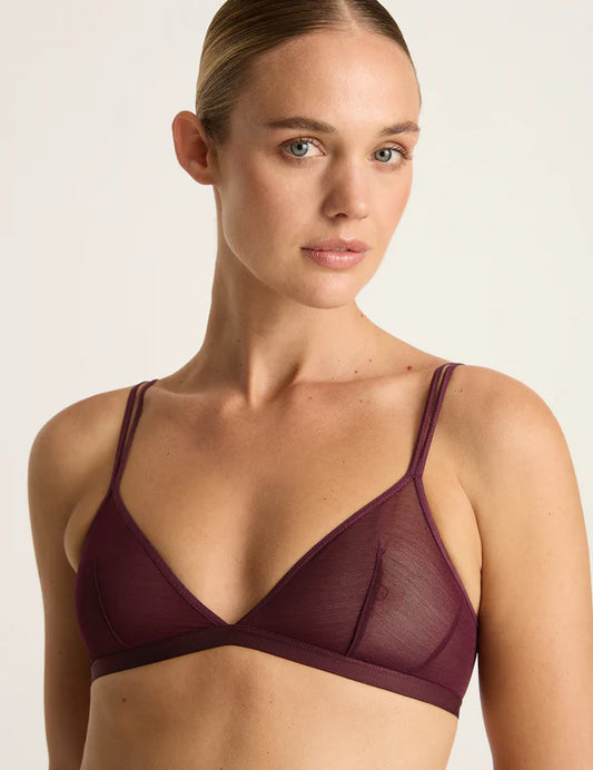 Woman wearing a maroon bralette against a plain background