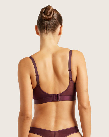 Woman wearing a maroon bra and underwear set on a light background