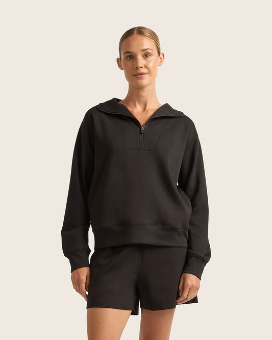 Woman wearing a black hoodie and shorts on a beige background