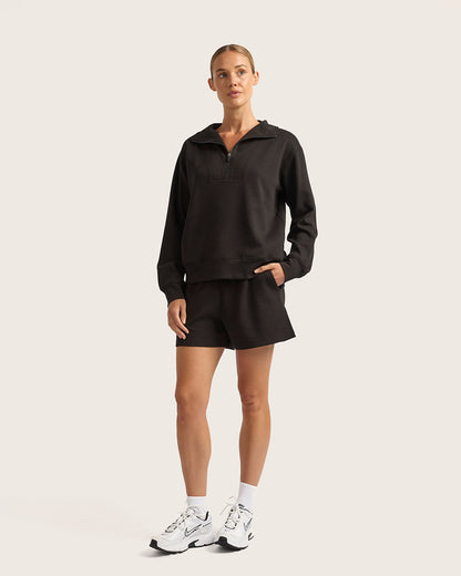 Woman wearing a black outfit with white sneakers on a light background