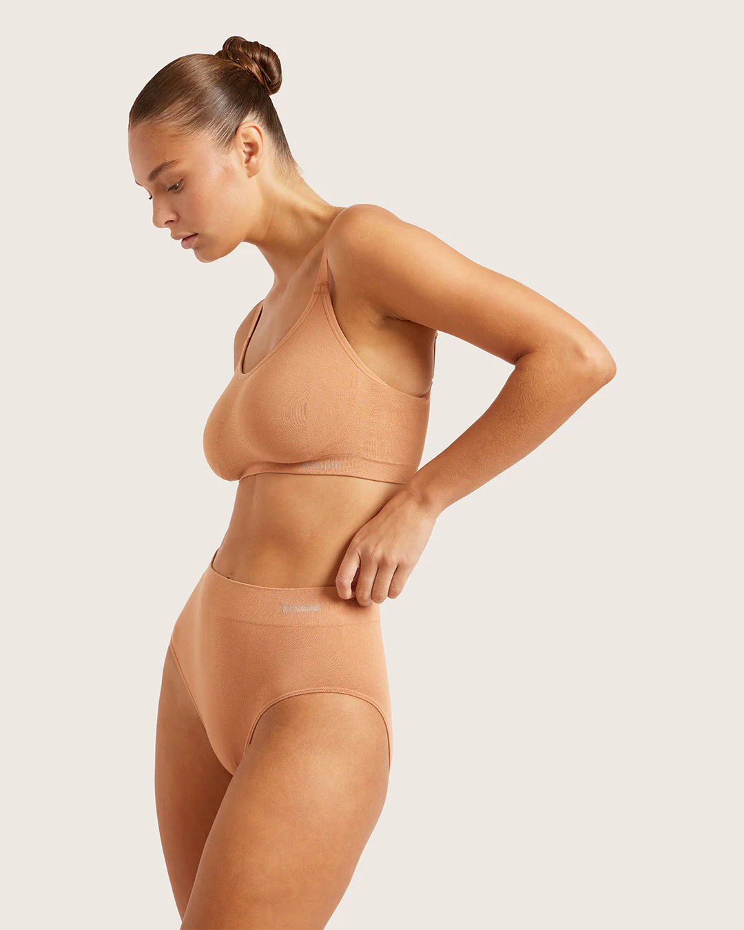 Woman wearing a beige shapewear set on a plain background