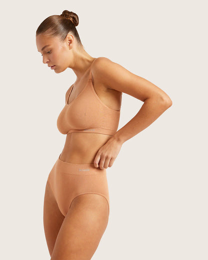 Woman wearing a beige shapewear set on a plain background