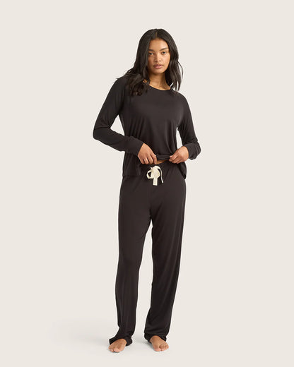 Woman wearing a black long-sleeve top and pants on a white background