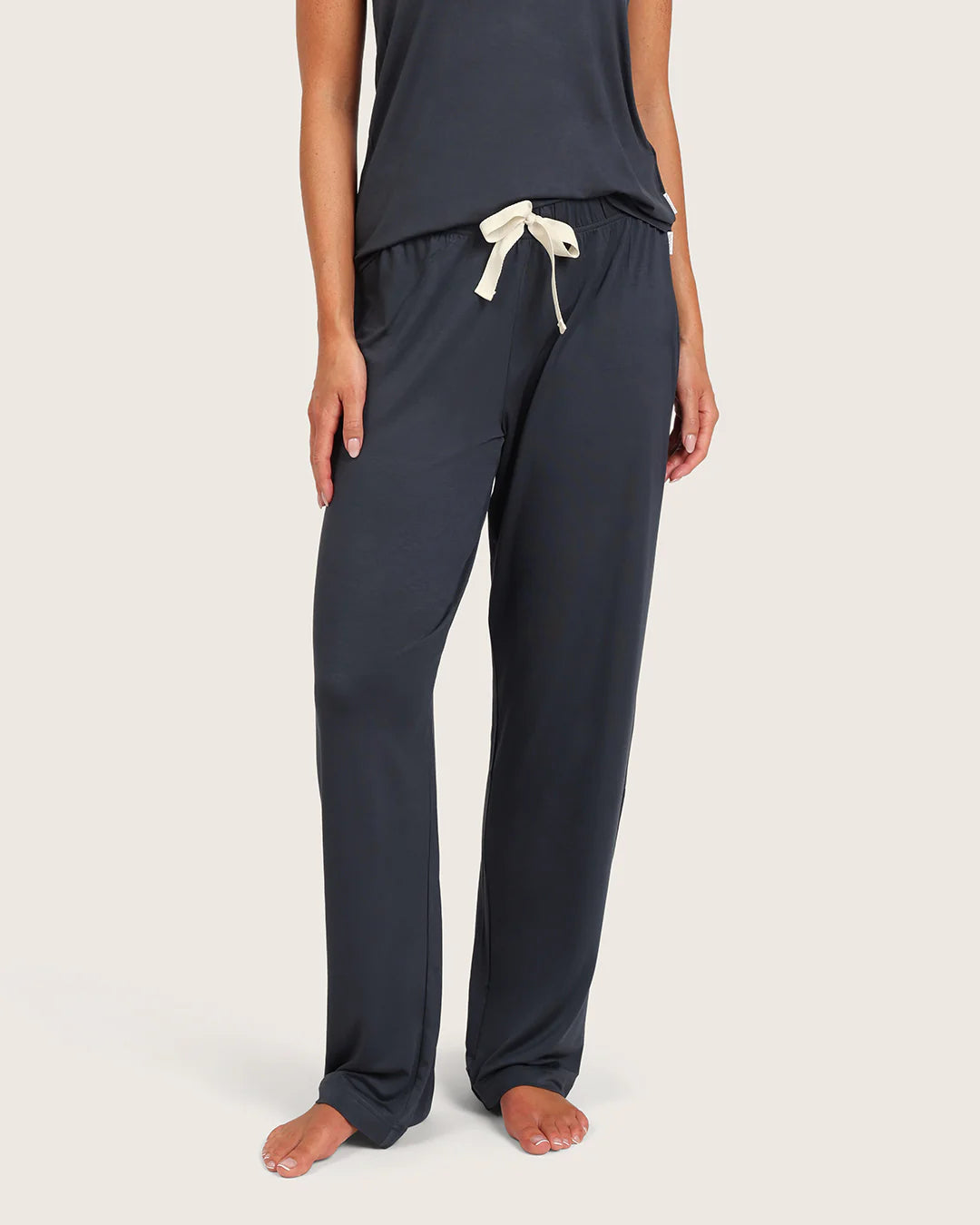 Navy blue pajama pants with a white drawstring on a beige background