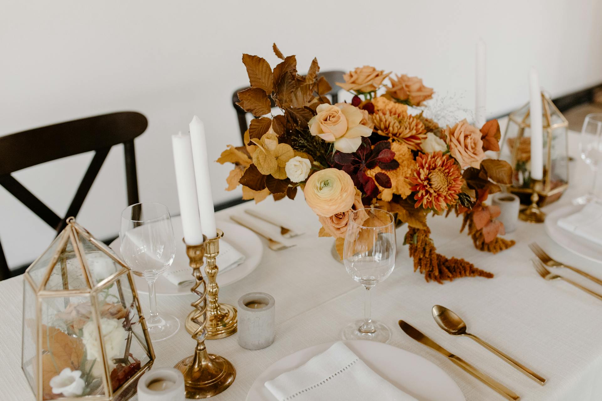 Elegant table setting with floral centerpiece, candles, and gold accents.
